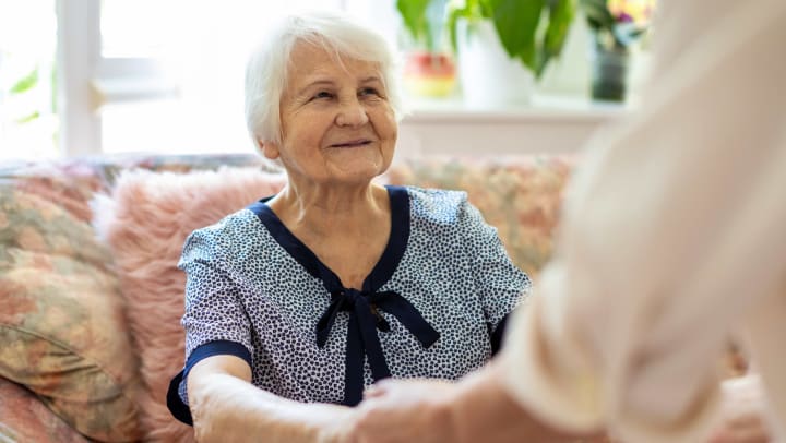 Senior woman smiling and holding hands with someone else