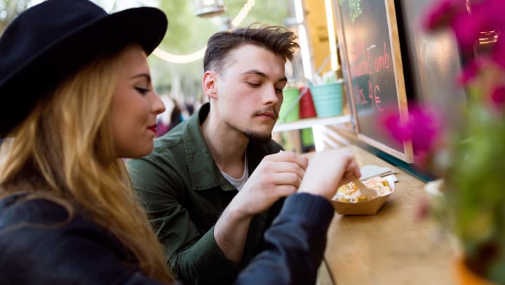 Young woman and man sharing food outside a food truck