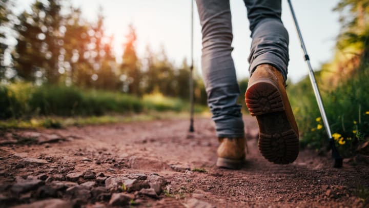 Close-up of back of legs and hiking boots as person walks on mountain trail