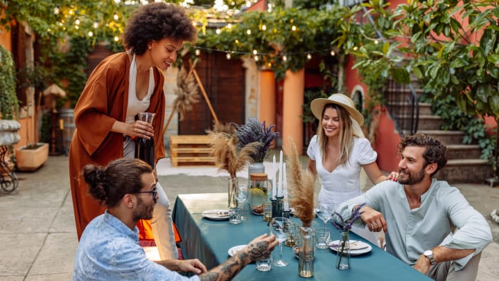 Group of friends sitting around a decorated table outdoors.