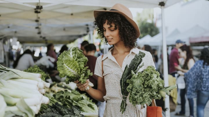 Beautiful woman buying kale at a farmers market.