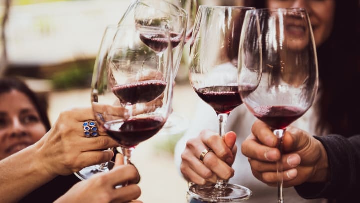 Happy friends toasting with red wine