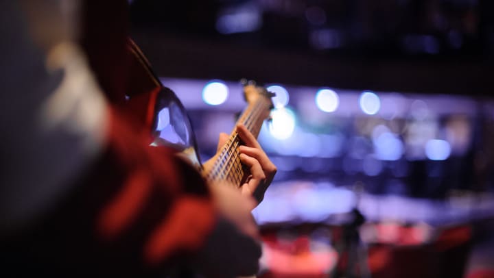Person standing with a guitar in his hands on the dark background of blue lights