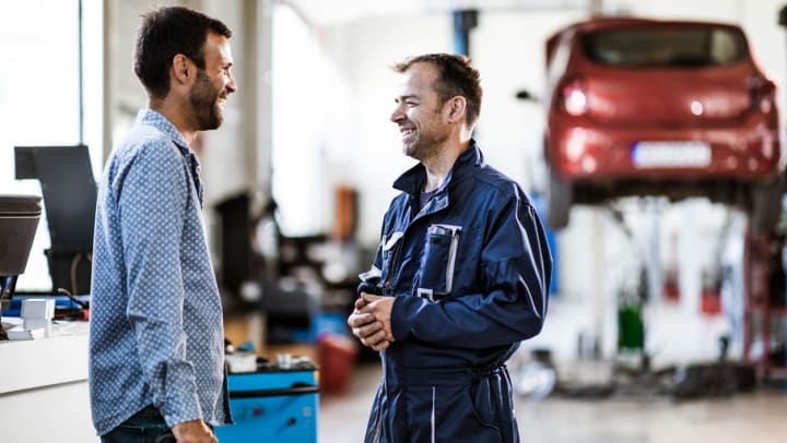 Man speaking with a mechanic in an auto repair shop in Spring.