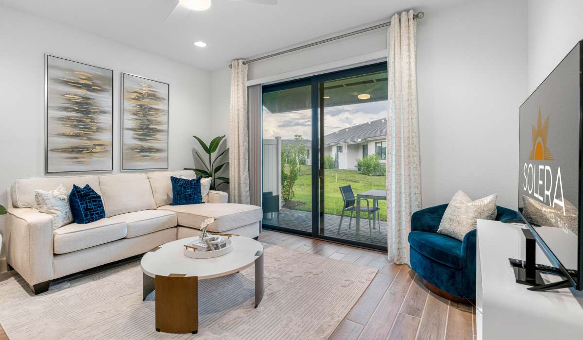 Bright living room with wood-style flooring and patio access, featuring a cozy sofa and modern decor at Solera at Avalon Trails in Delray Beach, Florida 