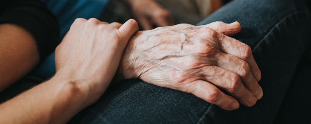 A hand resting on another hand at The Peaks at South Jordan Memory Care in South Jordan, Utah