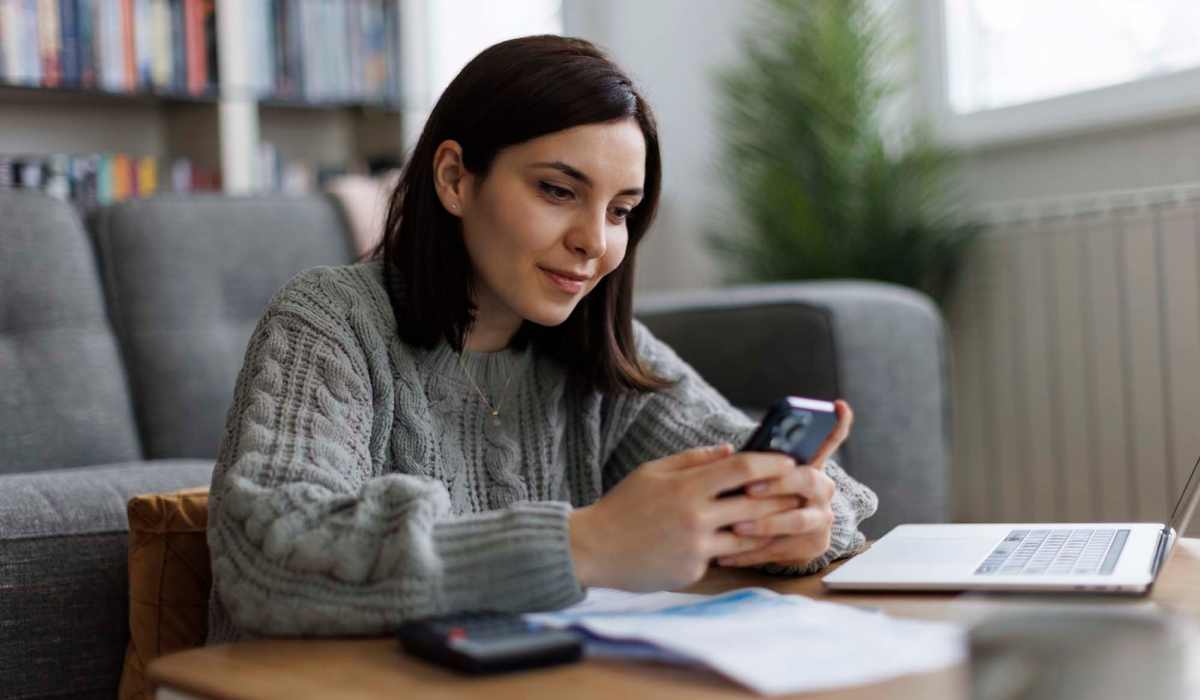 Resident making online payment in spacious living room at Walnut Apartments in Philadelphia, Pennsylvania