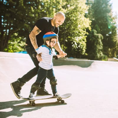 A father teaching his son how to skateboard at a park near Cascade Village in Joint Base Lewis McChord, Washington