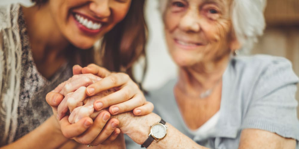 A family member holding a resident's hand at Mission Healthcare at Renton in Renton, Washington.
