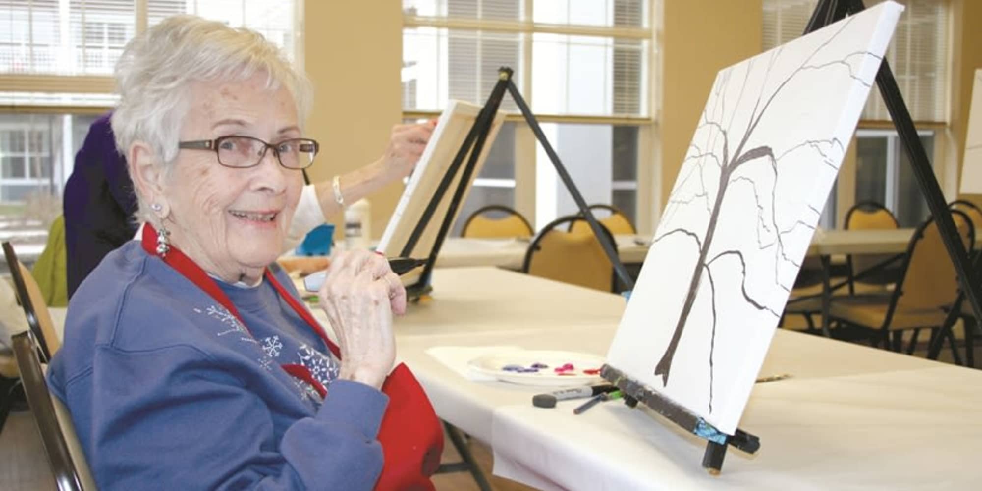 A resident from Fairview Estates Gracious Retirement Living in Hopkinton, Massachusetts painting a tree