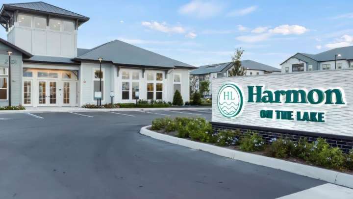 The entrance to Harmon on the Lake apartments in Apopka, Florida, featuring modern buildings and a large sign.