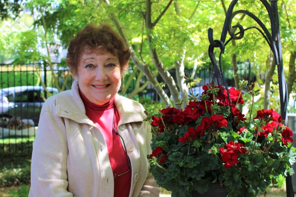 Resident enjoying the outdoor courtyard flowers at Campus Commons Senior Living in Sacramento, California
