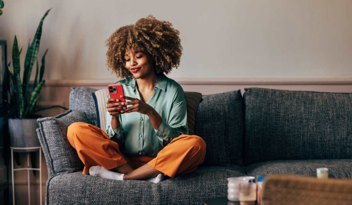 Resident looking at her phone in her living room at Waters Edge in Sacramento, California
