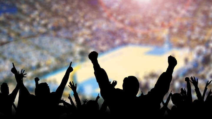 Silhouette of a crowd cheering during a basketball game.