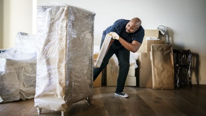 Man wraps furniture in plastic so it can be stored at {{location_name}}. 