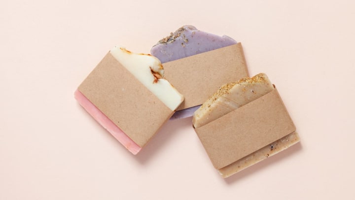 Different handmade soaps in Gilbert sitting on a table wrapped in brown paper. 