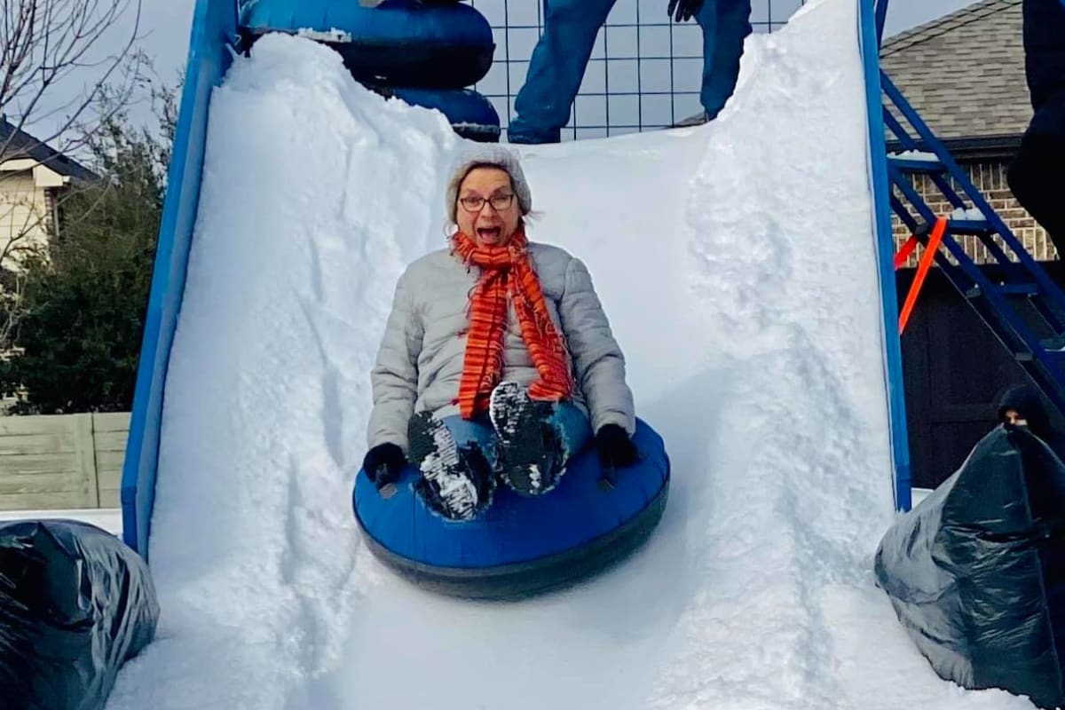 Laughing woman sliding down snow slide at BB Living Harvest in Argyle, Texas