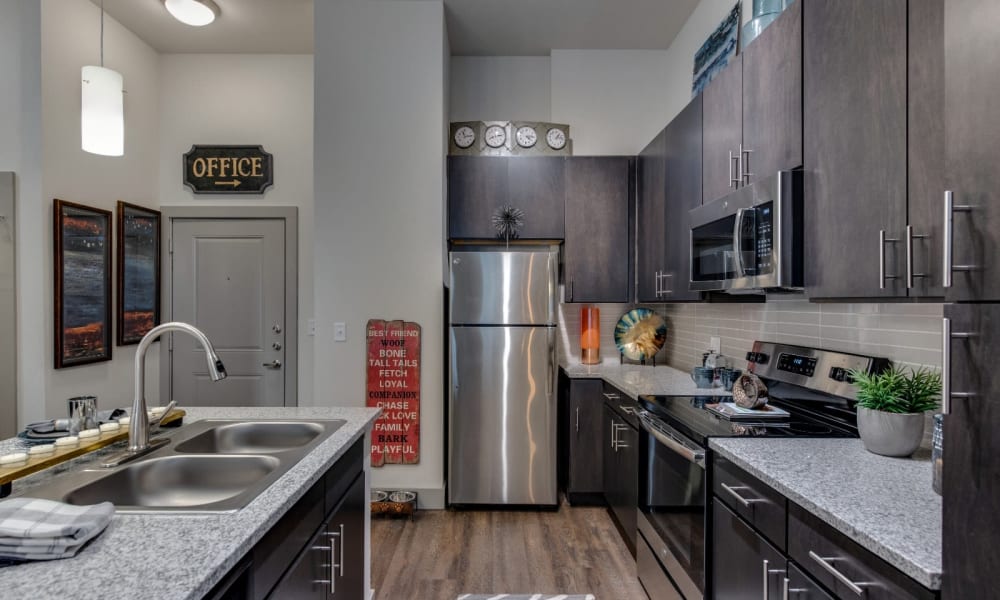 Large kitchen with stainless steel appliances and wood style flooring at Bellrock Upper North in Haltom City, Texas