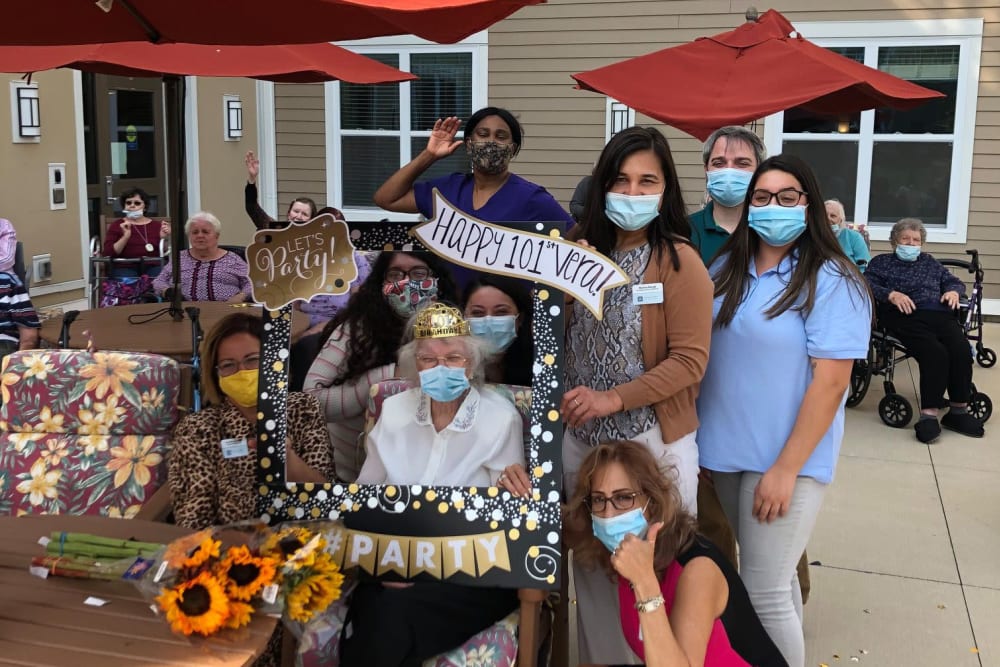 Resident and masked caretakers celebrating outside at Anthology of Blue Ash in Blue Ash, Ohio