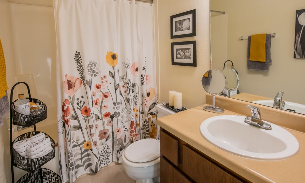 Well-lit bathroom with large vanity mirror in model home at Sugarberry Apartments in Tulsa, Oklahoma