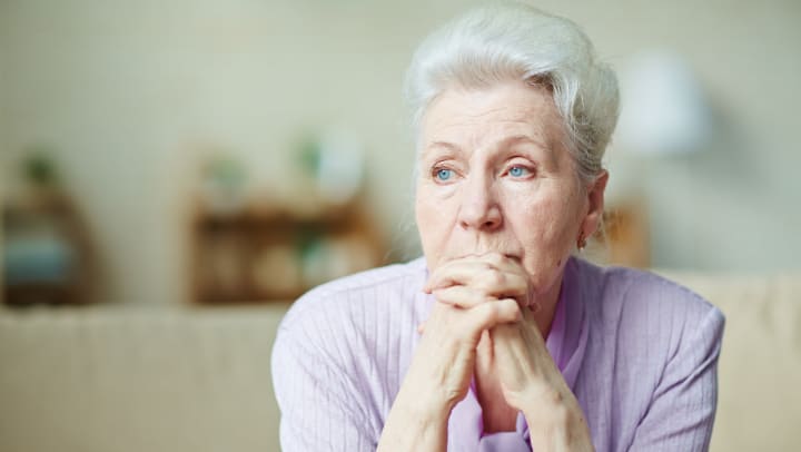 Elderly woman looking away with hands crossed on their chin