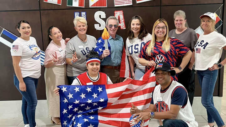 Atrium at Liberty Park staff wearing american themed attire standing with an emerican flag smiling
