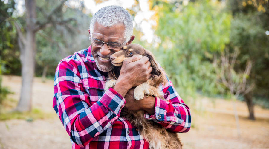 Happy resident hugging a visiting puppy at Cascade Park Gardens Memory Care in Tacoma, Washington