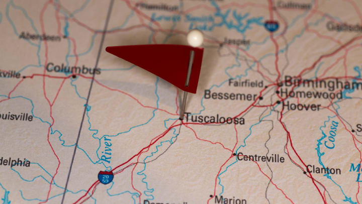 A pin with a red flag pinpoints Tuscaloosa, Alabama, on a map