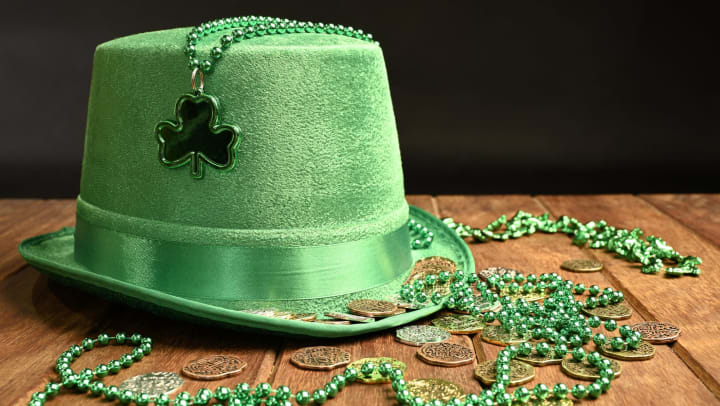 Green hat and necklaces and lucky coins on black background