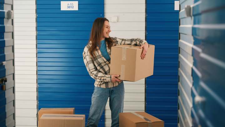Woman holding boxes as she’s ready to store items in a storage unit