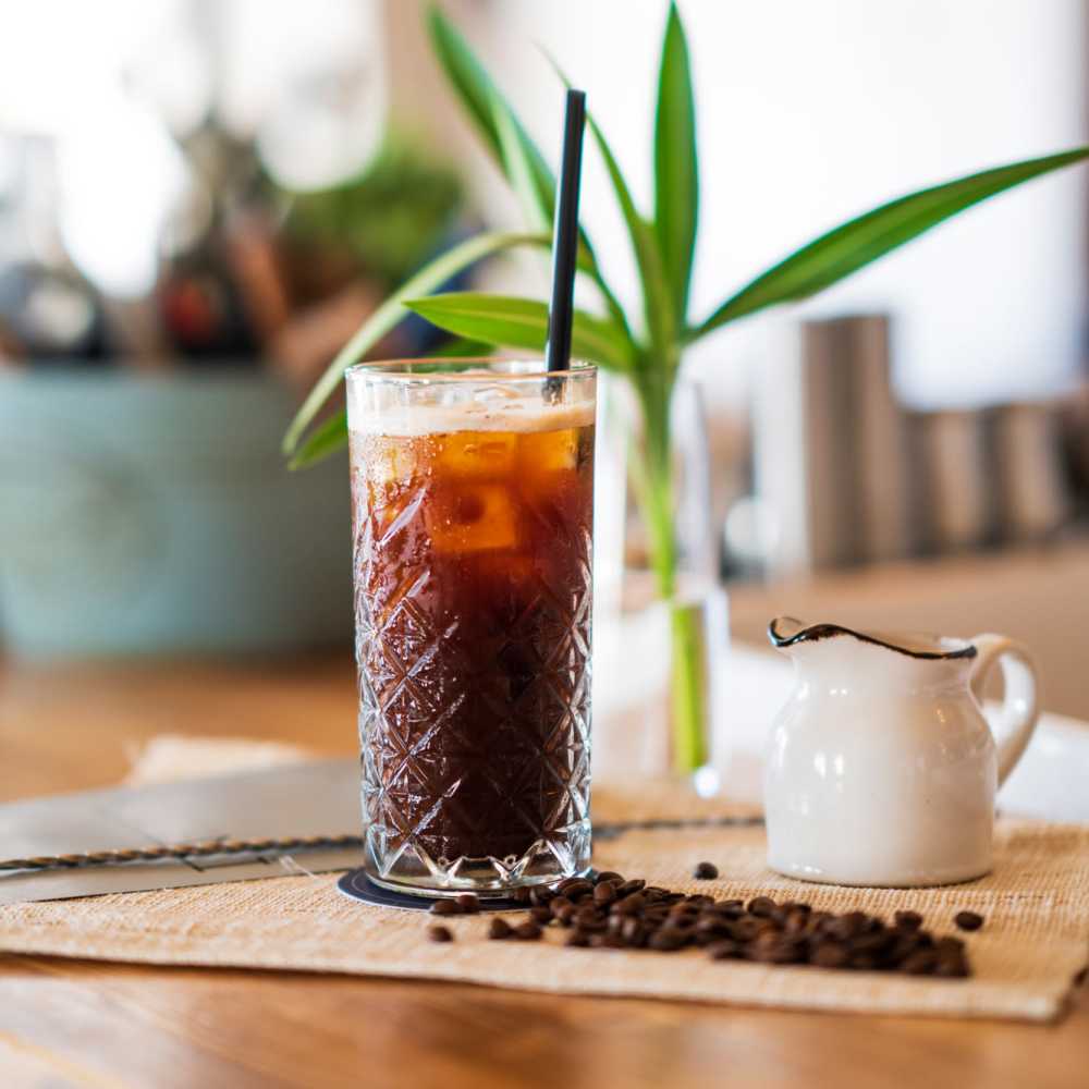 Iced coffee on a wooden table with coffee beans at Park at Kingsview Village in Germantown, Maryland