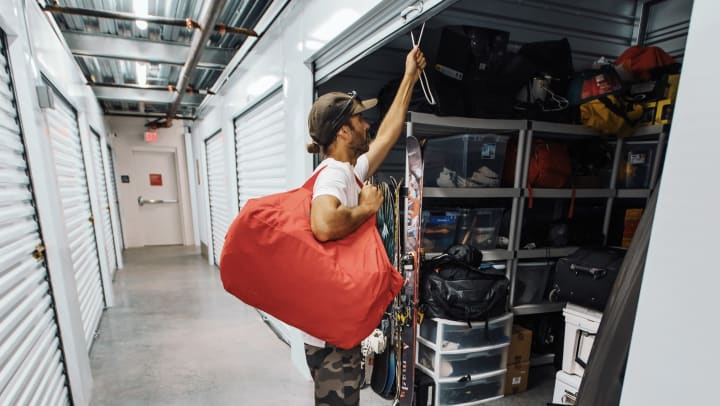 Person with large duffel bag closing up a storage room full of adventure gear.