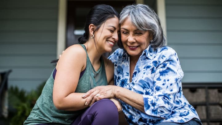 Senior woman and adult woman smiling and hugging on a porch