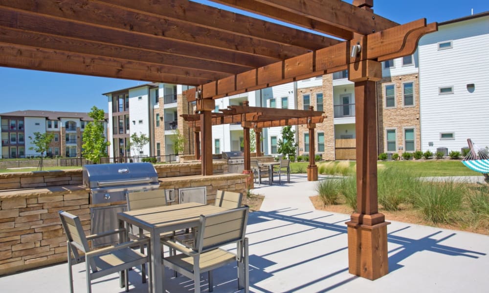 Grilling area with tables and chairs near the pool at Bellrock Upper North in Haltom City, Texas