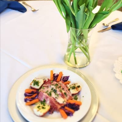 Plated meal next to flowers in a vase at The Sycamore of River Falls in River Falls, Wisconsin