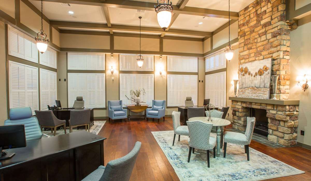 Community office area with chairs, tables, large windows and fireplace at Cobblestone Park in Manvel, Texas