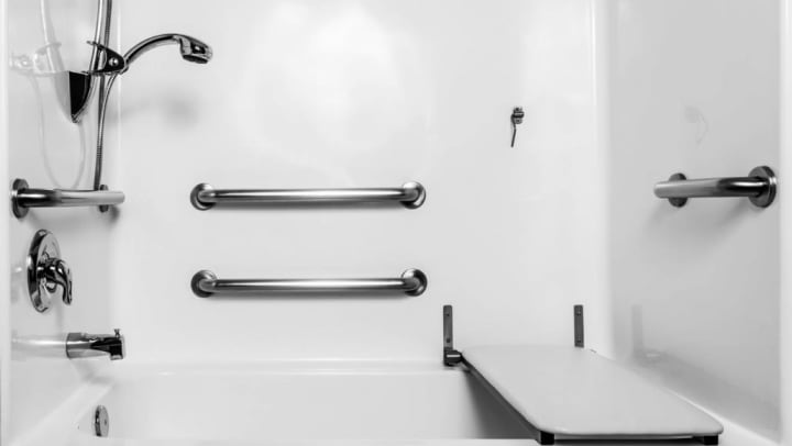 A bathroom shower with hand rails, bench, and safety features at {{location_name}} in {{location_city}}, {{location_state_name}}