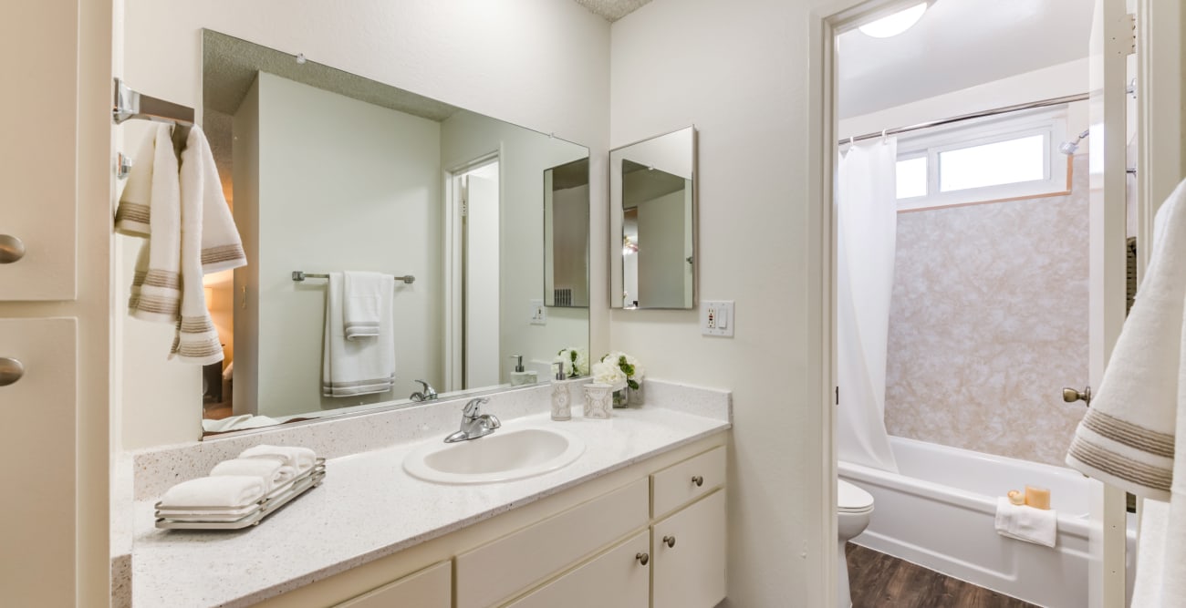 Spacious bathroom with large vanity, plank flooring, and white cabinets at The Windsor in Sherman Oaks, California