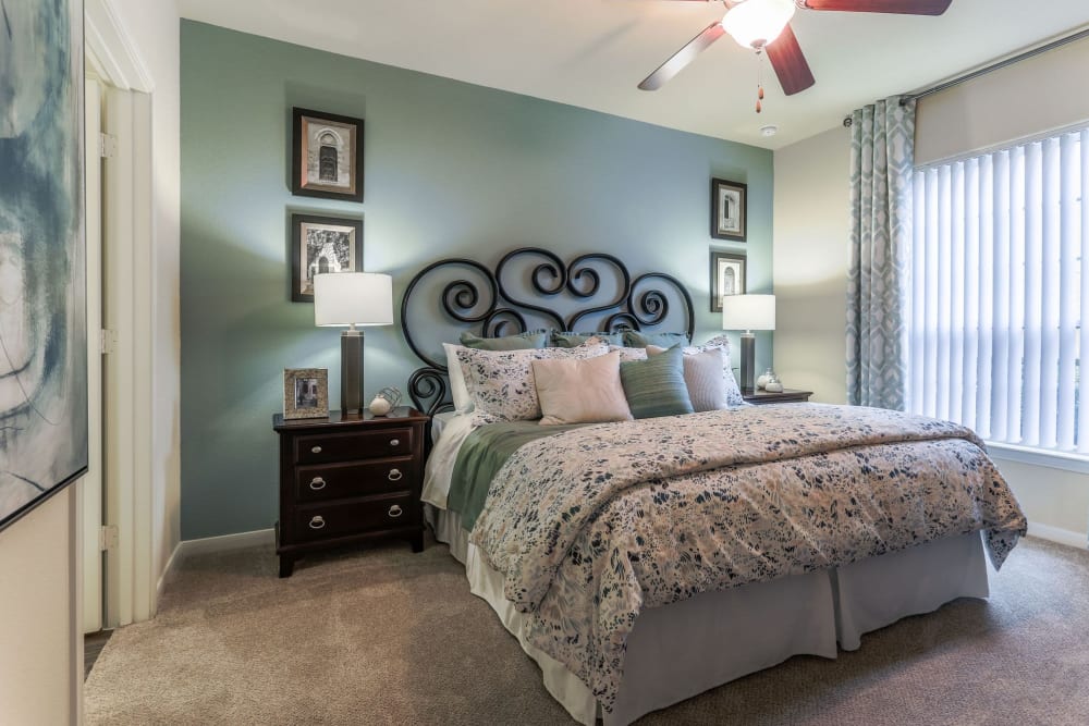 Model home's primary bedroom with an accent wall and draped bay windows at Amalfi at Tuscan Lakes in League City, Texas