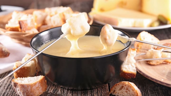 two skewers with bread dipped in a bowl of melted cheese | fondue in Tampa