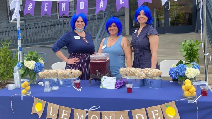 Employees wearing blue wigs and selling lemonade