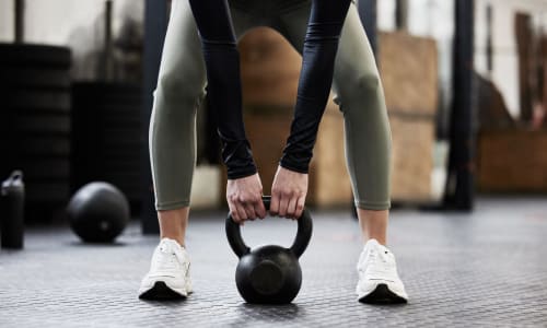 Resident using a kettle bell in the fitness center at Adelaide Pines in Concord, California