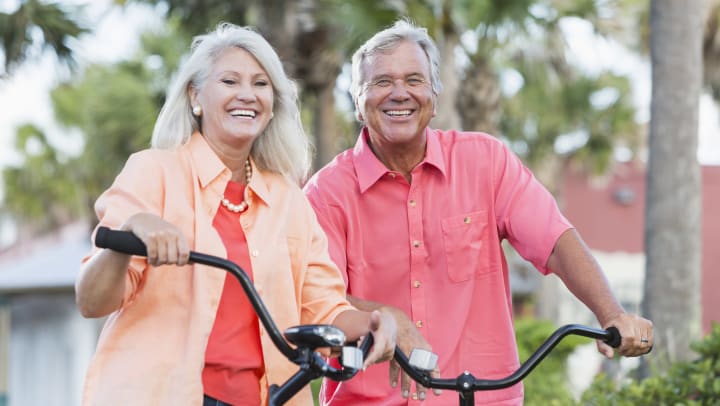 Two seniors outside sitting on bikes smiling