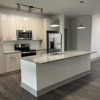 Kitchen with solid surface counters, gray cabinetry and stainless appliances at The Dartmouth North Hills in Raleigh, North Carolina