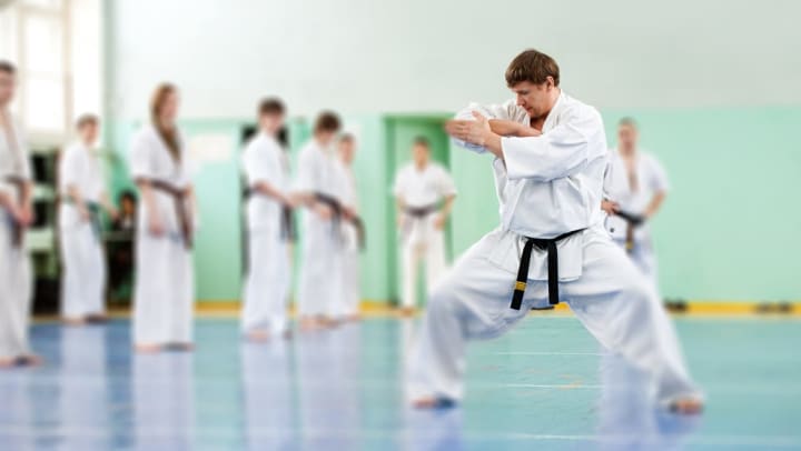 A black belt-wearing karate instructor demonstrates his stance to a class of martial arts students | martial art studios in Sachse