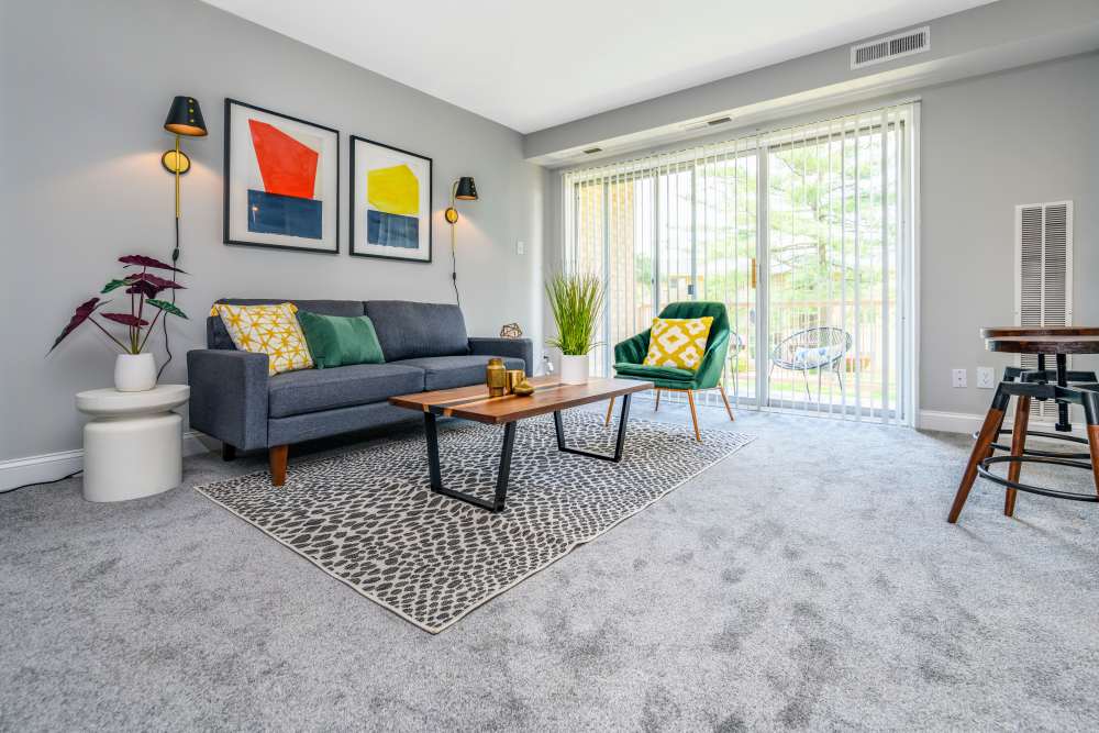 Spacious living room with couch and glass door leading to balcony at Beacon Hill Apartments in Alexandria, Virginia