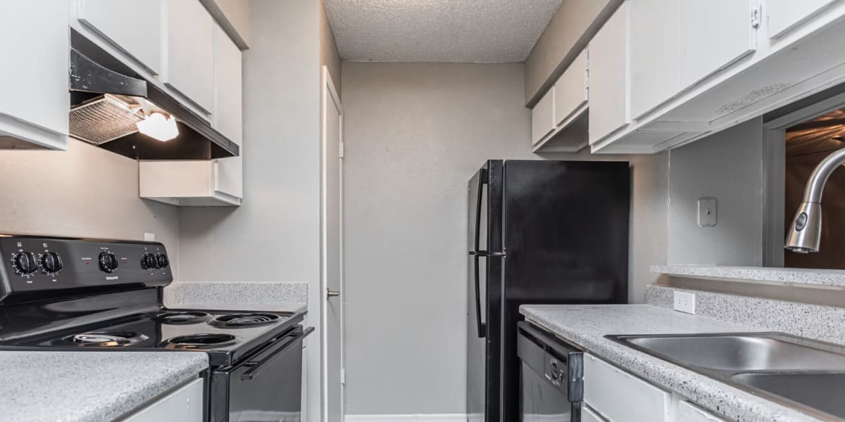 Fully equipped kitchen with granite countertops black appliances like a refrigerator, range, sink and dishwasher at Villa Nueva in San Antonio, Texas