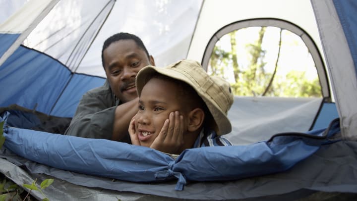 Father smiling at his son while they lay in a tent