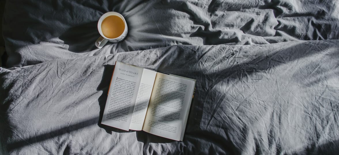 Coffee and book on a bed at Arcadia Decatur in Decatur, Georgia