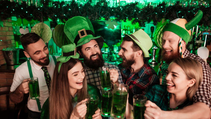 A group of friends ( 4 men 2 women) in a St. Patrick’s Day themed bar, dressed in green. 